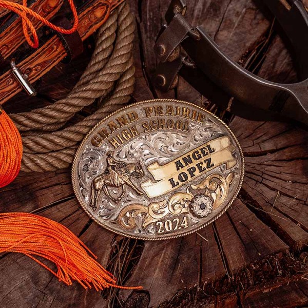 A custom western belt buckle for Grand Prairie High School with personalized name featuring a cowgirl figure on  a hand engraved silver base